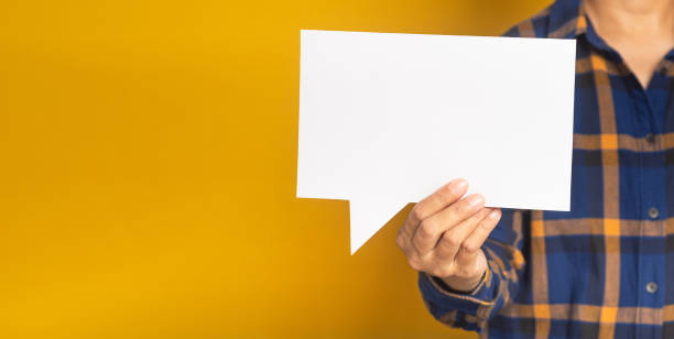 istock Businessman in a blue shirt holding an empty speech bubble paper while standing on a yellow background. 1485964328