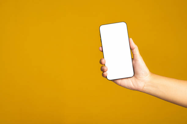 istock Hand holding a mobile phone with copy space for text standing on a yellow background. 1485964814