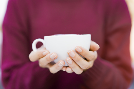 Beautiful Asian young woman holding a coffee cup on a hands close up. Woman enjoy drinking a coffee in morining with breakfast.