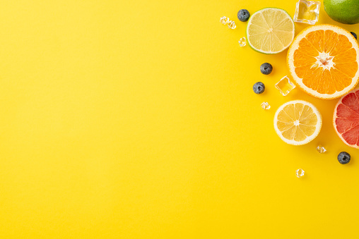 Yellow bliss concept. Top view of zesty citrus fruits - orange, lemon, lime, and grapefruit on a sunny yellow background with empty space for advertising