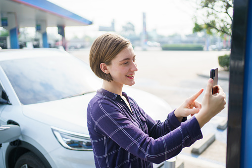 Unrecognizable caucasian white woman holding the CCS 2 EV charging connector at EV charging station, woman preparing an EV - electric vehicle charging connector for recharge a vehicle.