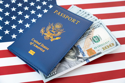 US American passport and money dollars on flag background. purchase of citizenship concept, work in the USA, loan issuance, money exchange