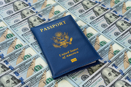 an American passport against the background of a large pile of American dollars. The concept of lending or buying fake documents