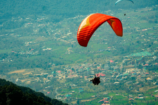 istock Paraglider flying over town and mountains. 1485967671