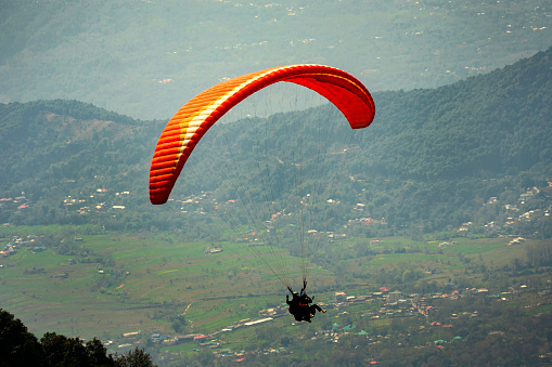 Paraglider flying over town and bir billing mountains. beautiful view of bir-billing mountains paragliding site in himachal pradesh.