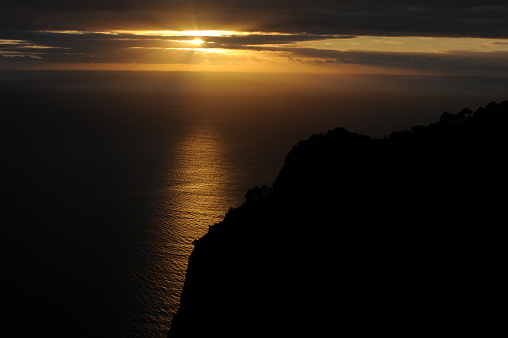 Sunset over the Atlantic Ocean from a cliff with dark clouds  in Maderia Island, Portugal, Europe