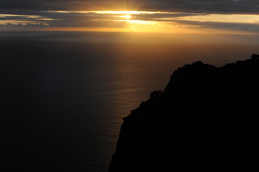 Sunset over the Atlantic Ocean from a cliff with dark clouds  in Maderia Island, Portugal, Europe
