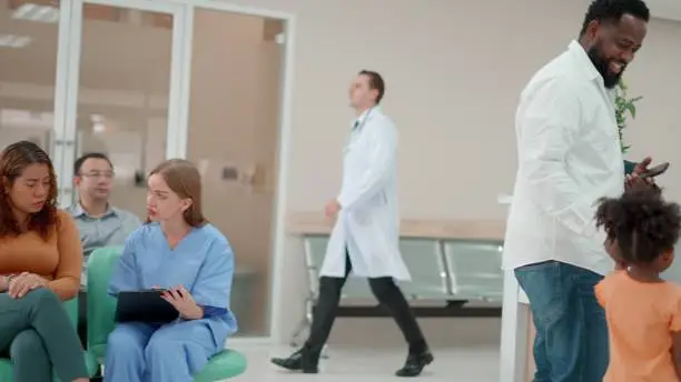 Photo of Female doctor or nurse consultations for the patients, presentations check-up health or sharing test results or inquire about personal information or medical conditions. Multiracial group of patients waiting in lobby for checkup at hospital.