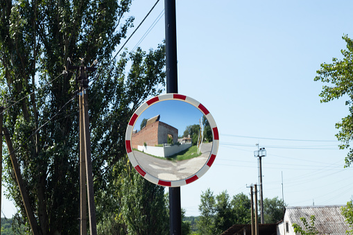 curved road ferris mirror hanging on a pillar near a road in Ukraine in the afternoon