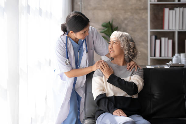 Asian female doctor or nurse gently guide and care for elderly patient at home, giving warm encouragement and consolation. stock photo