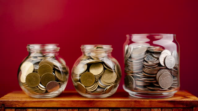 Saving coins in a glass jar money increase income income salary wages coin bank investment profit financial review