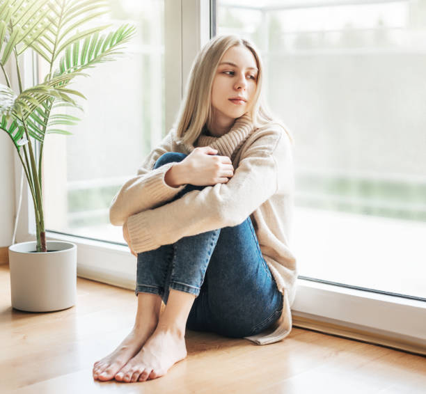 istock Sad girl near window thinking about something 1485978645