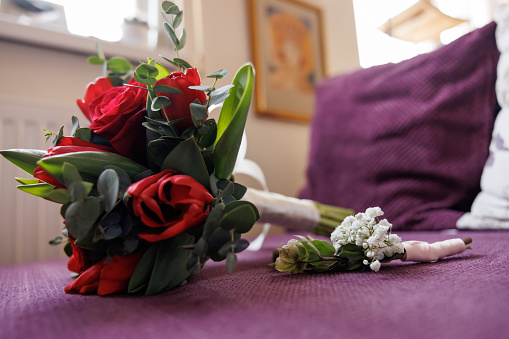Red rose and lily of the valley bouquets on sofa at home