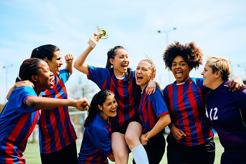 Excited female players celebrating winning a trophy on soccer tournament.