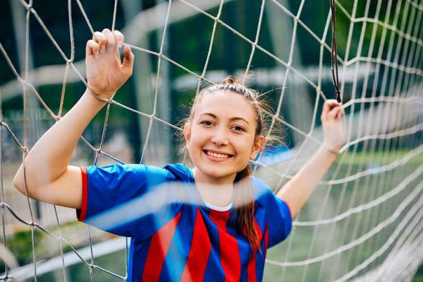 istock Happy female player looking at camera through soccer goal net. 1485983513