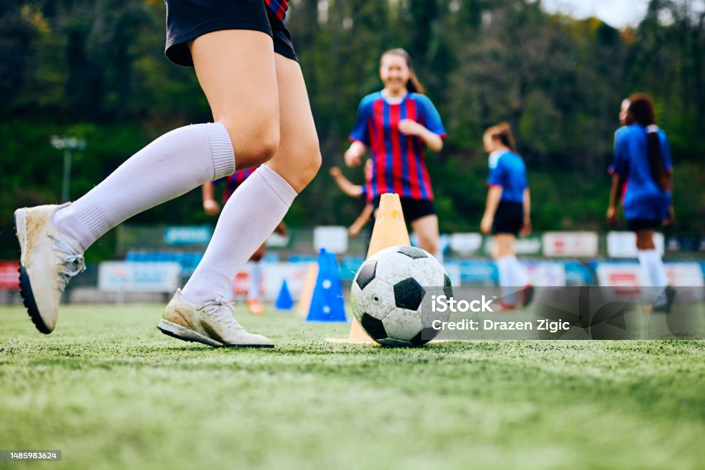 Close up of female player exercising with ball on soccer training at the stadium. Close up of female soccer player with a ball during practice on playing field. Copy space. Women's Soccer Stock Photo