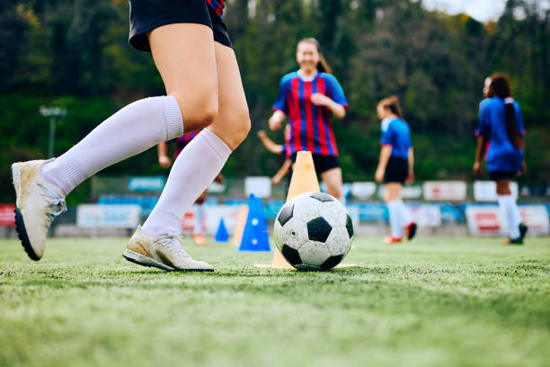 Close up of female player exercising with ball on soccer training at the stadium. Close up of female soccer player with a ball during practice on playing field. Copy space. womens soccer stock pictures, royalty-free photos & images