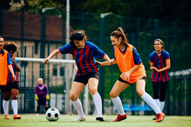 Female players in action during practice on soccer pitch. Young sportswomen playing soccer on training at the stadium. club soccer photos stock pictures, royalty-free photos & images