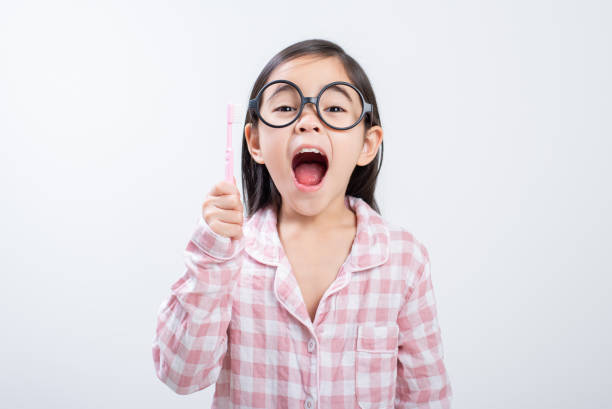 istock little girl Asia brushing teeth happily white background 1485987954