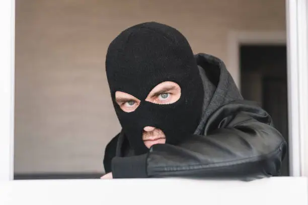 Photo of a threatening look on the criminal's face. A dangerous criminal looks into the camera. Glabitel is a thief in a black jacket and jacket. Apartment theft or robbery concept