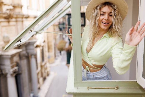 istock Beautiful young woman waving from the window 1485992652