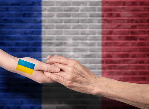 Handshake between France and Ukraine. The flag of France extends a helping hand to Ukraine.