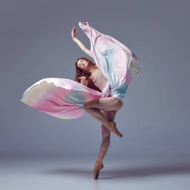 istock Weightless easy jump. Sensual ballerina with dancing with fabric over grey studio background. Contemporary dance. Flying with silk dress 1485996019