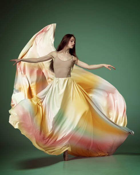 istock Young ballerina dancing elegant, grace movement with flying fabric over dark green studio background. Rainbow dress 1485996089