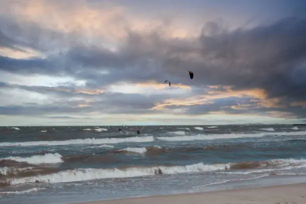 Photo of Wing Foiling kitesurfing wind surfing water outdoor sport in Baltic sea Dark blue clouds ocean water surface with foam waves before storm, dramatic seascape