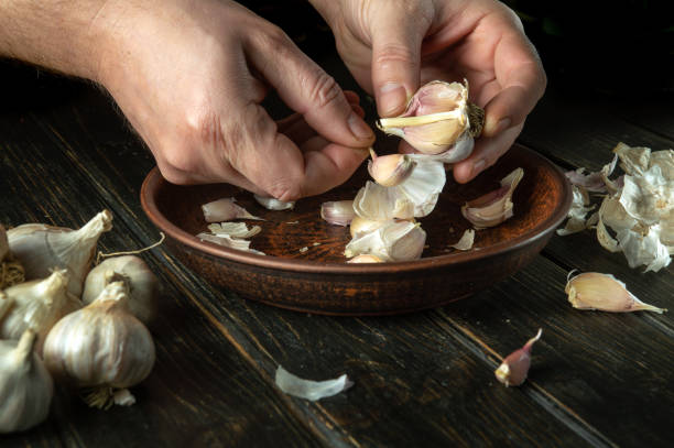 istock The cook cleans the garlic in a vintage plate on the kitchen table before preparing a vegetarian meal. Tasty recipe concept on dark background 1485998993