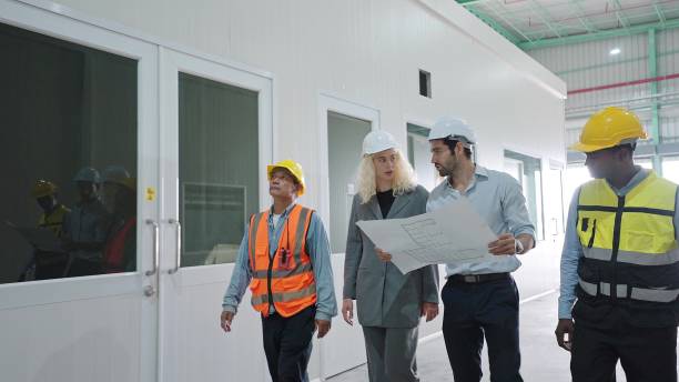 istock Warehouse team discussing while walking in warehouse. Employees working with warehouse management walking in a large distribution centre 1486002950
