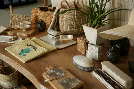 Souvenir shop display, sustainable handmade gifts - rattan and shell gifts on the wooden table at the resort shop