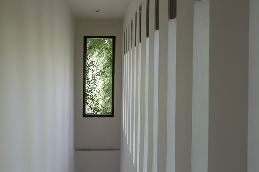 Modern white narrow hallway with windows on the side wall