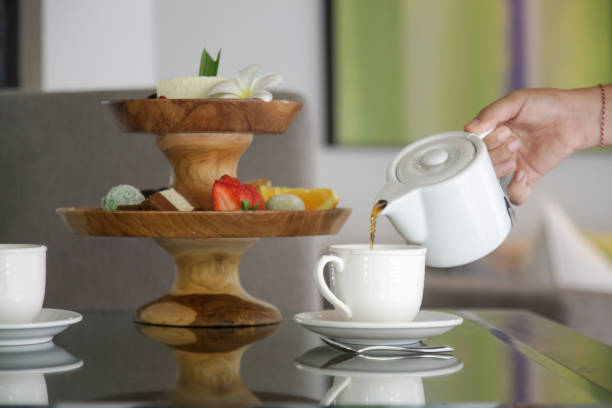 istock Woman hand holding a teapot and pouring tea in a white ceramic cup 1486004436