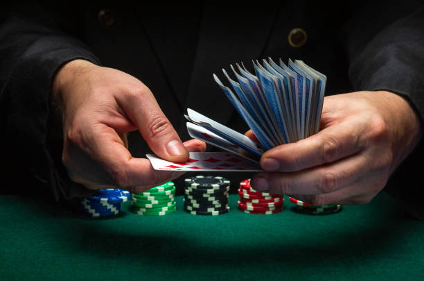 A professional dealer or croupier quickly shuffles playing cards in a club at a green table with playing chips. The concept of a successful poker game in a casino A professional dealer or croupier quickly shuffles playing cards in a club at a green table with playing chips. The concept of a successful poker game in a casino. dibs stock pictures, royalty-free photos & images