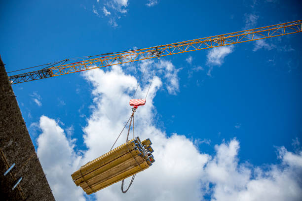 Low angle view of crane carrying construction materials to a construction site against clear blue sky in Graz, Austria.