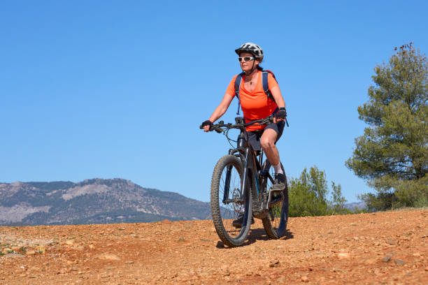 woman on electric mountain bike in the pine tree forest near Granada, Spain nice, active senior woman riding her electric mountain bike in the pine tree forests near Granada, Andalusia, Spain via verde spain stock pictures, royalty-free photos & images