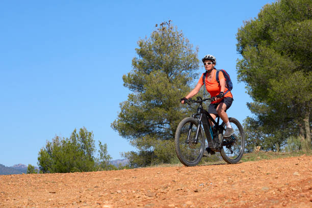 woman on electric mountain bike in the pine tree forest near Granada, Spain nice, active senior woman riding her electric mountain bike in the pine tree forests near Granada, Andalusia, Spain via verde spain stock pictures, royalty-free photos & images