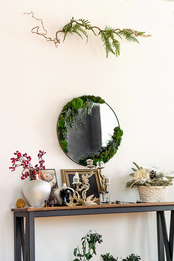 Interior decor made of natural materials.Round mirror decorated with stabilized moss and leaves.Biophilia design concept.