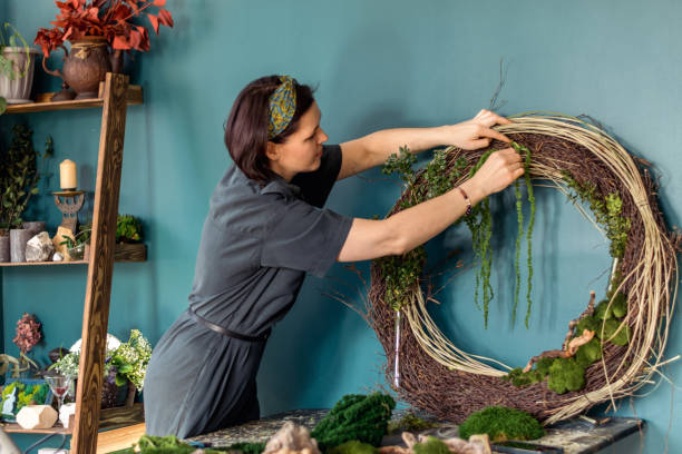 istock Attractive young woman makes home decor from natural materials in the workshop.The process of making a wreath of twigs,stabilized mossand leaves.Biophilia design concept 1486014805