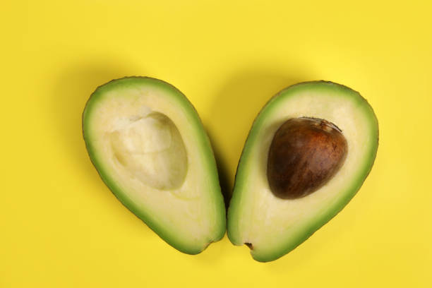 istock Ripe fresh green cut avocado on yellow background 1486015110