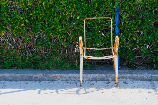 forgotten old metal rusty empty chair near green hedge. survivor and memory concept with copy space