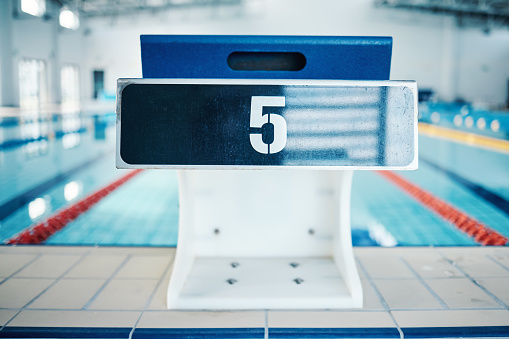Sports, swimming and number on diving board by pool for training, exercise and workout for triathlon competition. Fitness, motivation and five on professional podium ready for dive, start and race