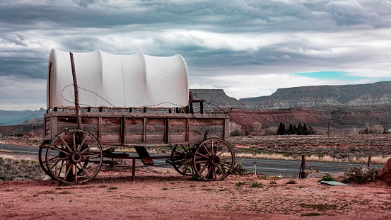 A rustic wooden covered wagon in a remote desert landscape with no people