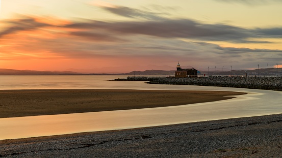 An awe-inspiring sunset with a vibrant orange and yellow sky over a picturesque lighthouse