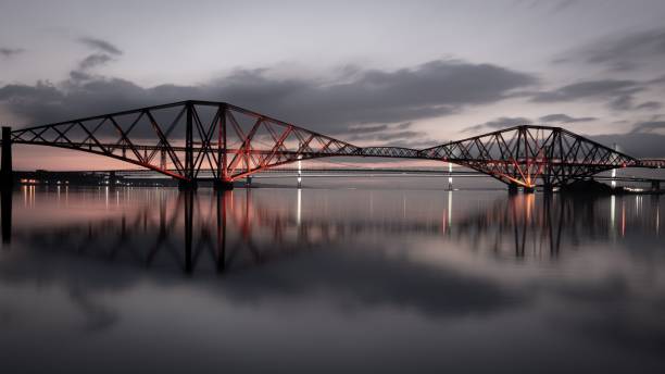 istock Aerial view of the Forth Bridge, spanning a river and illuminated with red lights at night 1486022460