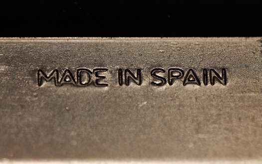 A closeup of a polished silver plate, engraved with the words 'Made in Spain' in a bold script