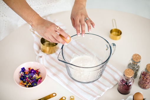 A female preparing a homemade batter from fresh ingredients laid around