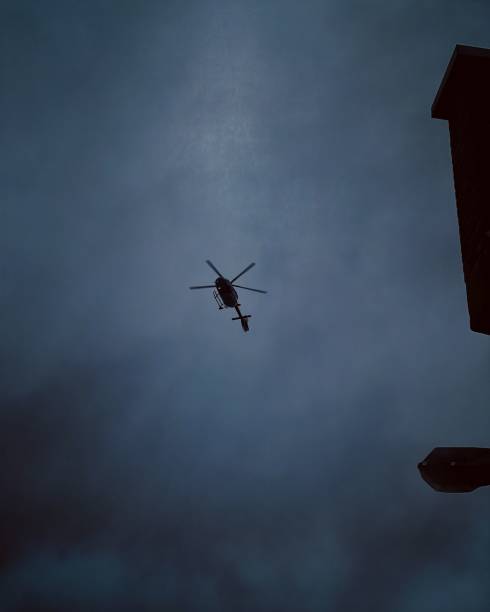 istock Low angle of a helicopter flying through a dark cloudy sky 1486023088