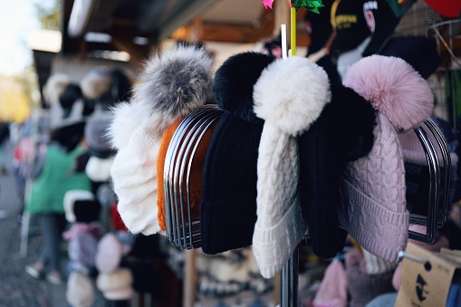 A variety of colorful hats with fluffy pom poms are on display for sale in a retail store